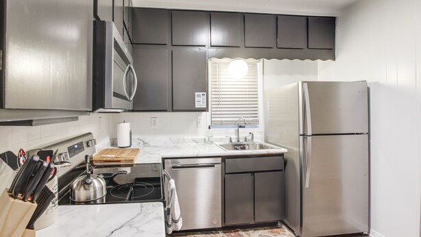 Una cocina moderna con electrodomésticos de acero inoxidable, lavavajillas y encimera de mármol.