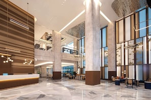 A spacious lobby with a reception desk, seating areas, and a high ceiling with modern lighting fixtures. - Hilton Garden Inn Beihai Railway Station (Beihai)