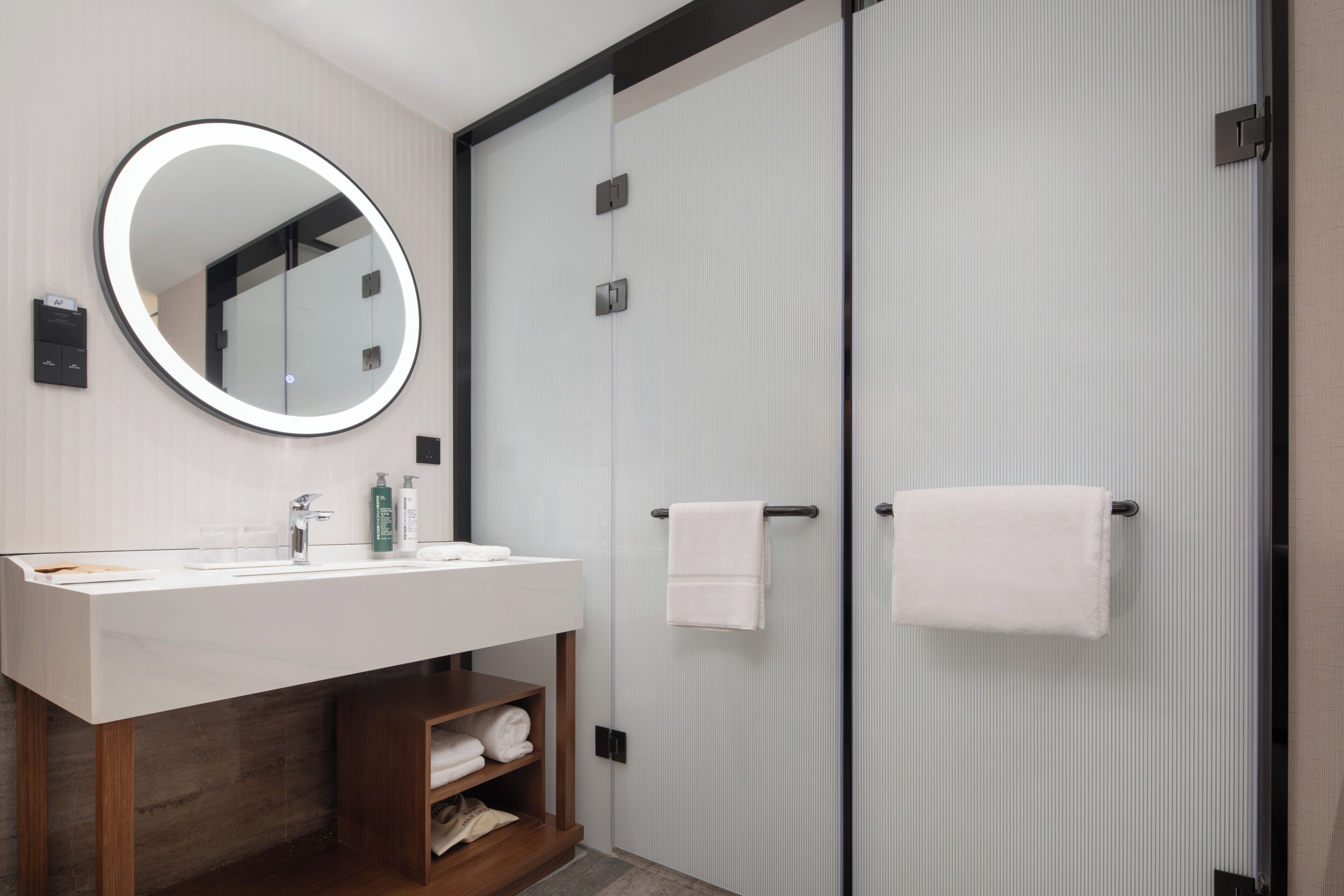 Ein modernes Badezimmer mit Waschbecken, Spiegel und Handtuchhalter.