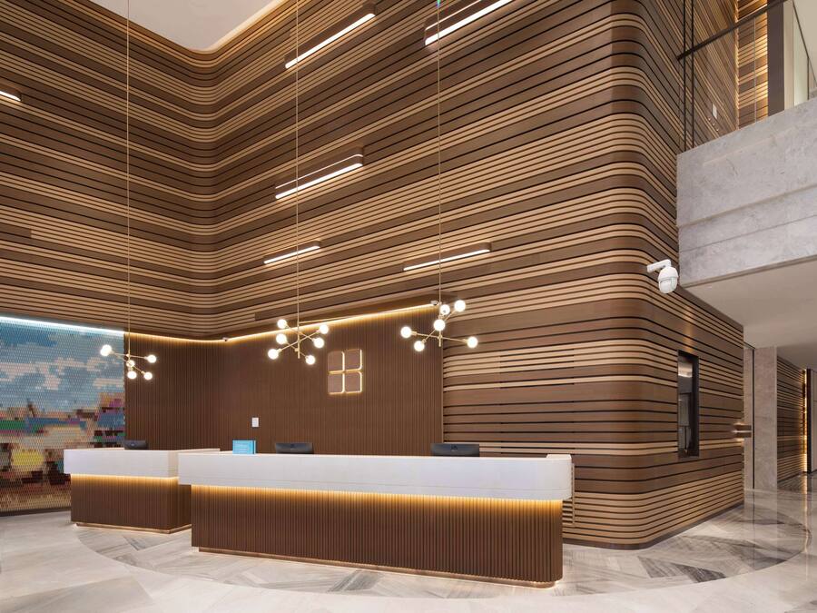 A modern reception area with a curved reception desk, wooden paneling, and pendant lighting.