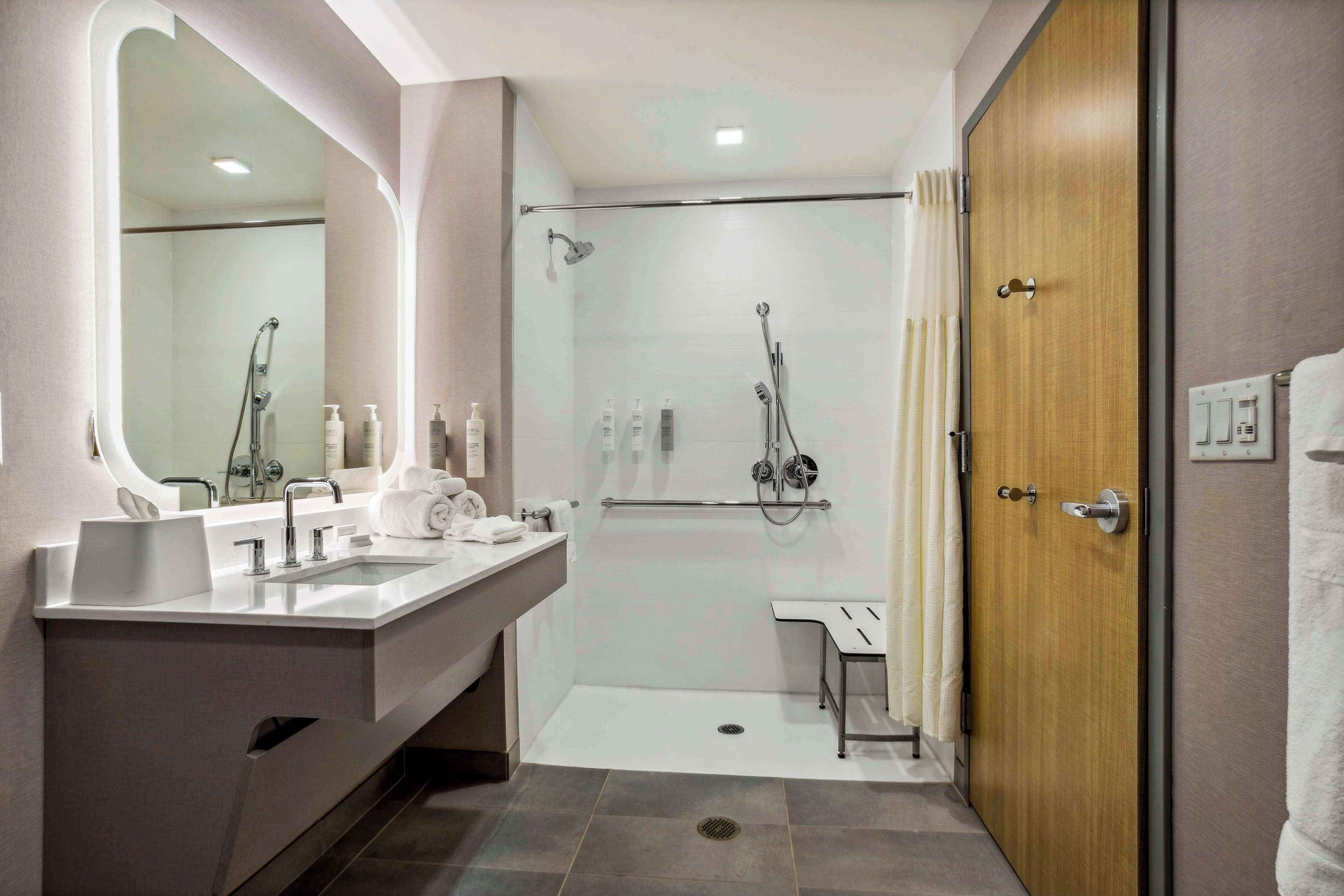 A modern bathroom with a shower, two sinks, a vanity, and a large mirror.