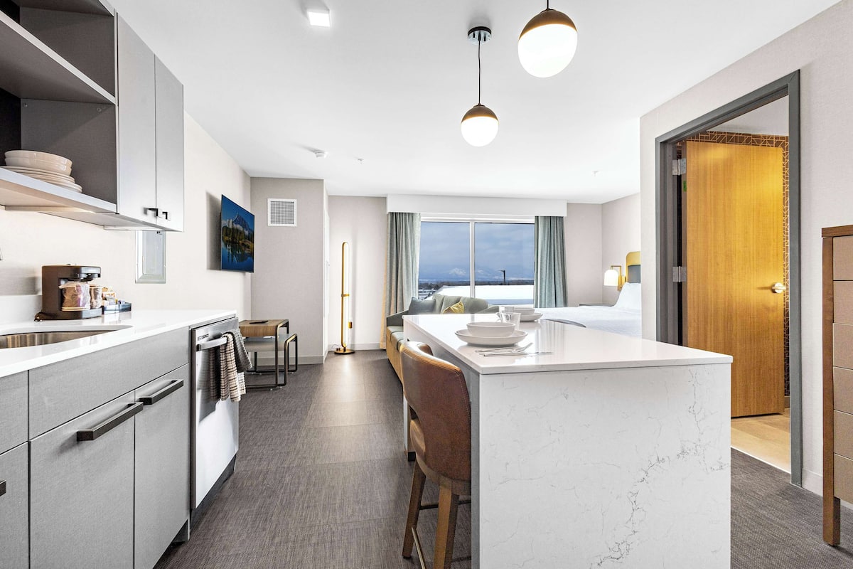 A modern kitchen with a central island, built-in appliances, and a view to the outside.