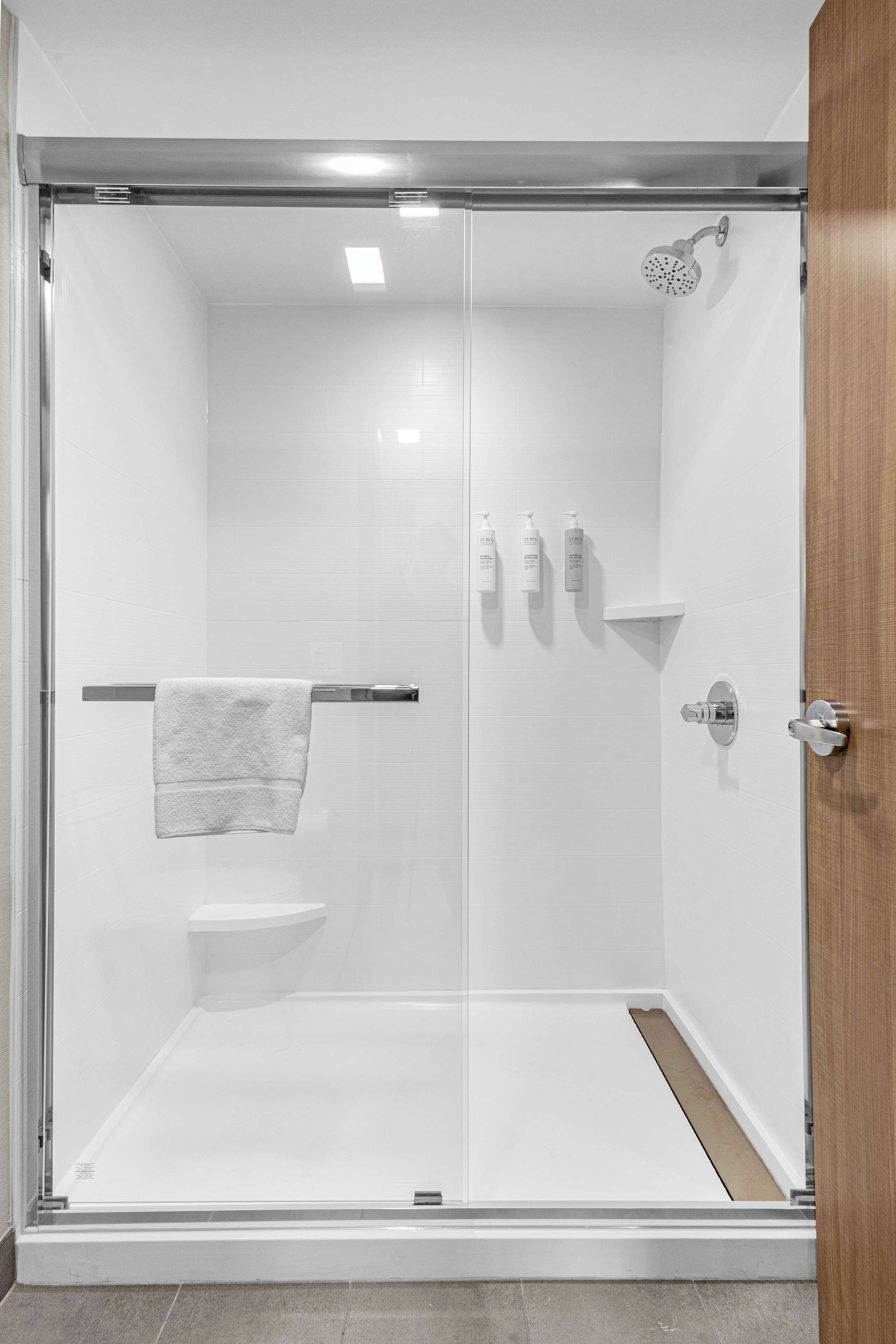 A modern shower enclosure with a glass door, a towel rack, and a showerhead.