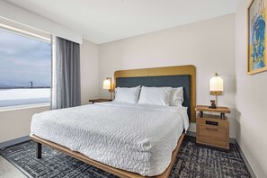 A hotel room with a large bed, two bedside tables with lamps, a view of the sea, and a framed picture on the wall. - Homewood Suites By Hilton Colorado Springs Airport (Colorado Springs)