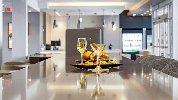 A modern dining area with a long table, two glasses of white wine, and a martini glass.