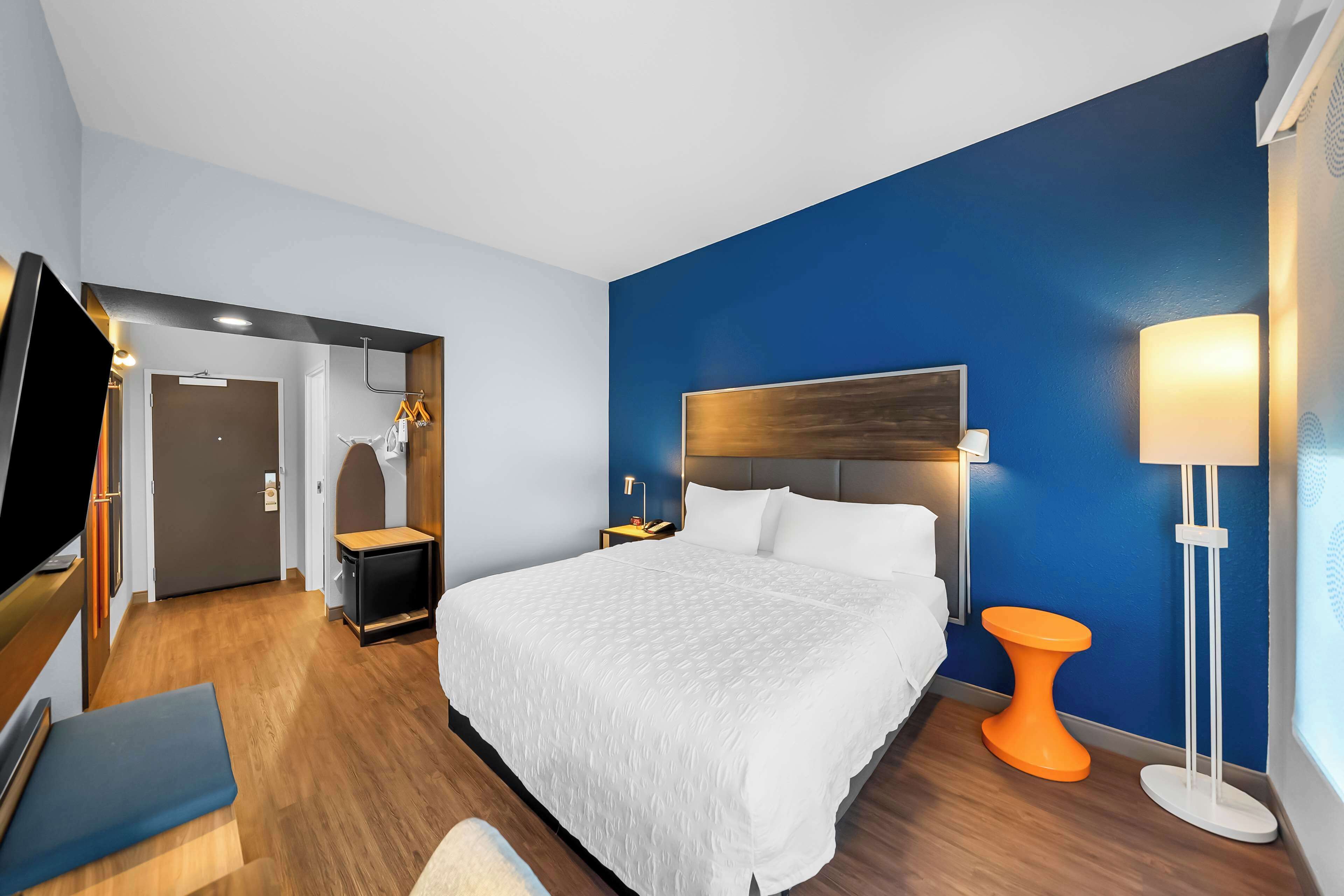 Quarto de hotel com uma cama grande, televisão, secretária e casa de banho.