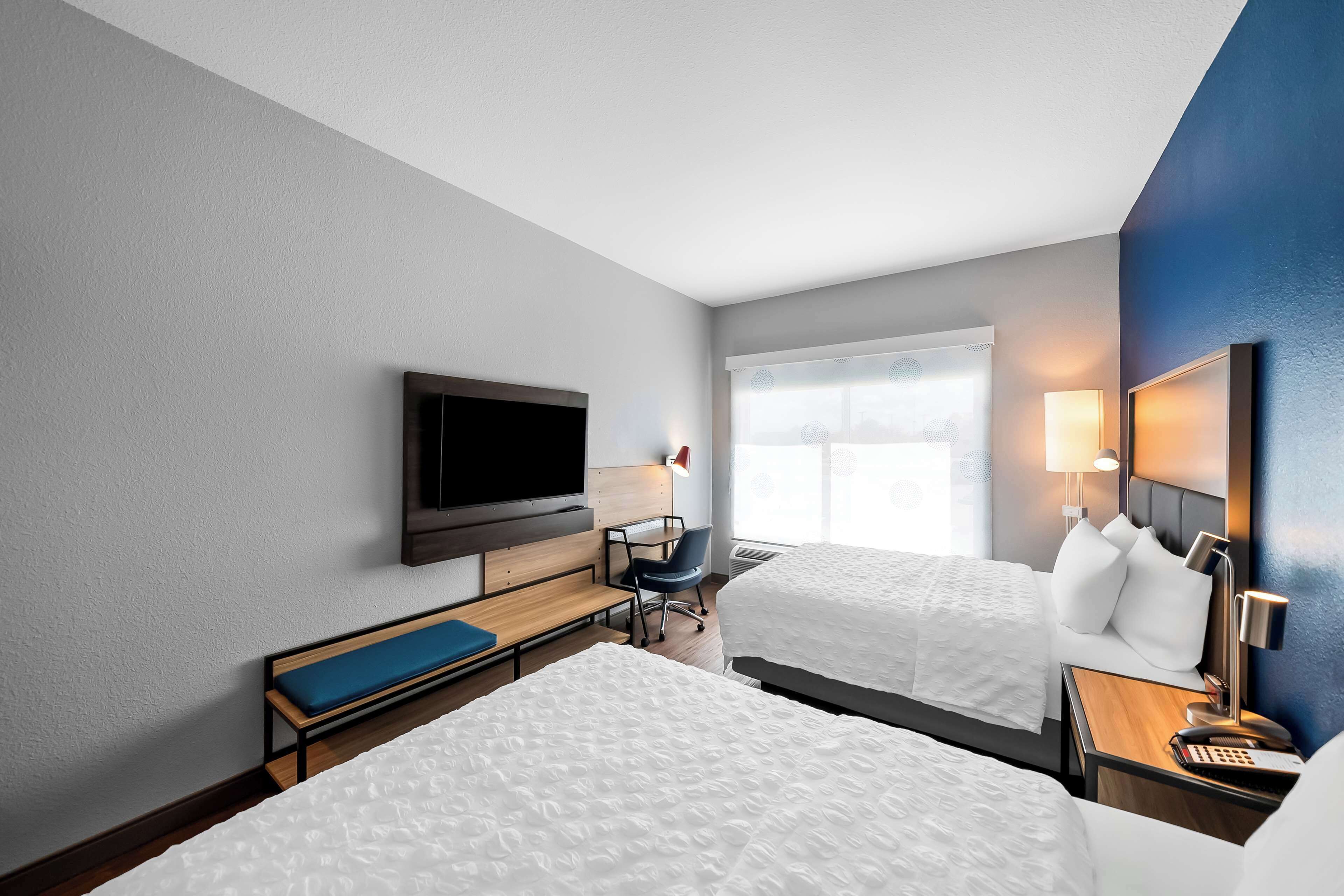 Une chambre d’hôtel avec deux lits, une télévision, un bureau et une chaise.