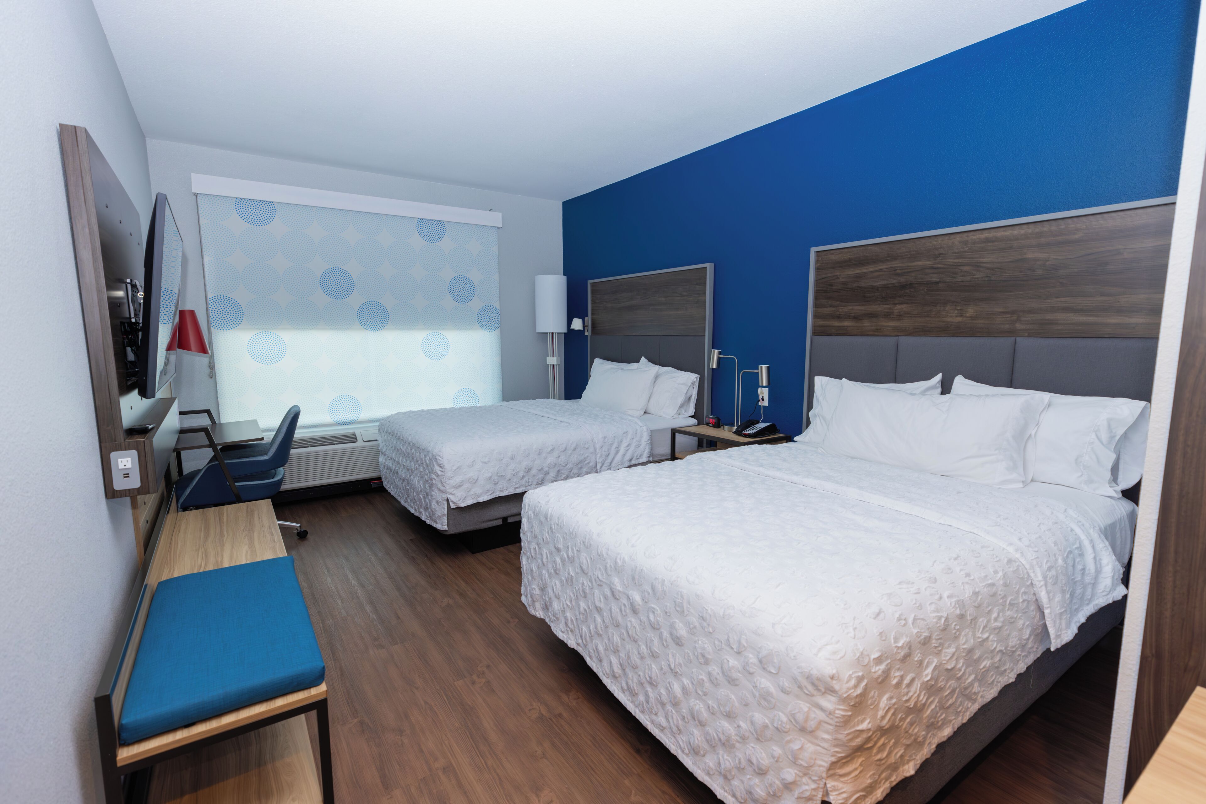 Una habitación de hotel con dos camas, un escritorio, una silla y un televisor.