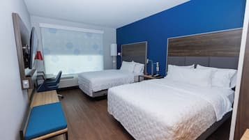Una habitación de hotel con dos camas, un escritorio, una silla y un televisor.
