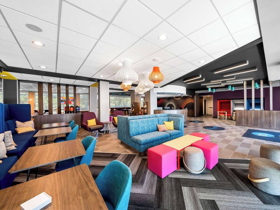 A modern lobby with seating areas, a reception desk, and a kitchen in the background.