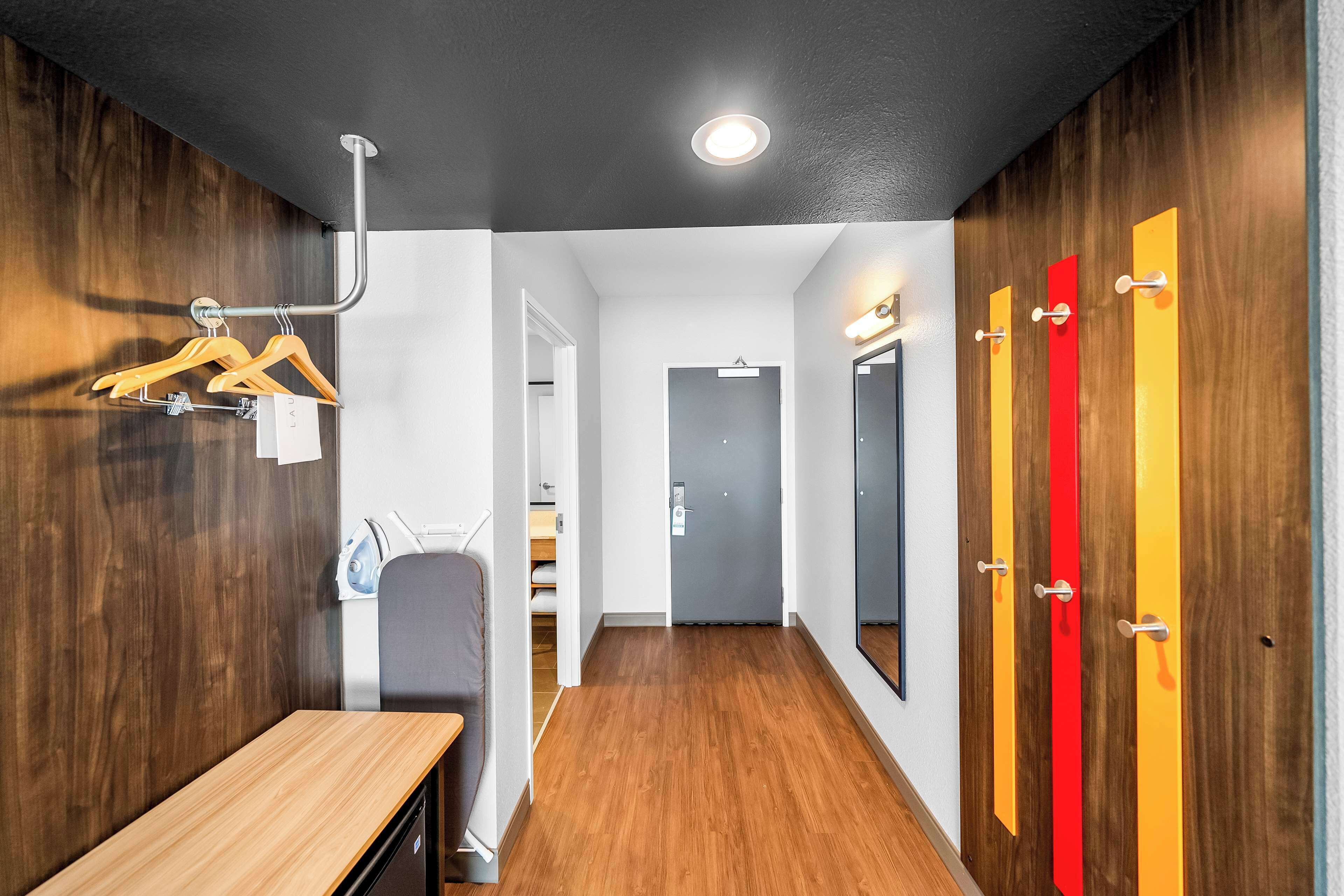 A hallway with a wooden desk, a coat rack, and lockers with colorful doors.