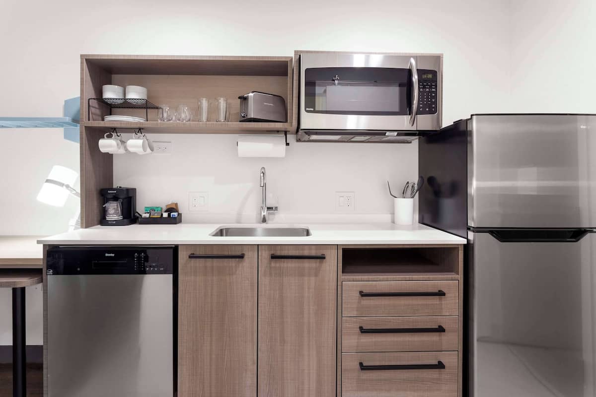A compact kitchen with a dishwasher, microwave, and refrigerator.