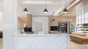 Ein Hotel-Rezeptionsbereich mit Marmor-Theke, einem Schild für 'Suite Shop' und einer Minibar.