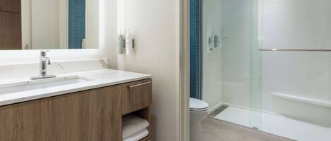 A modern bathroom with a wooden vanity, a large mirror, and a glass-enclosed shower area.