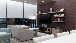 Ein modernes Wohnzimmer mit einer Couch, einem Couchtisch, einem an der Wand montierten Fernseher und Einbauschränken mit Dekorationsobjekten.