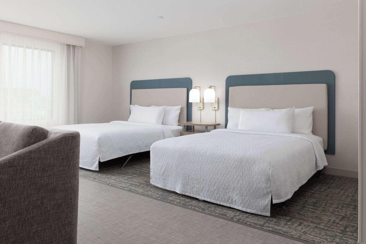 Ein Hotelzimmer mit zwei Betten, einem kleinen Tisch und einem Stuhl.