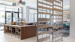 Ein modernes Café mit Holztresen, Barhocker und einer Glastheke.