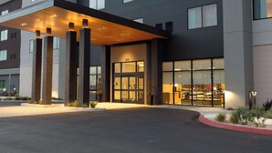 Ein moderner Hotel-Eingangsbereich mit der Beschilderung "HOMEWOOD SUITES by Hilton", einem überdachten Bereich und einer gut erkennbaren Eingangstür.