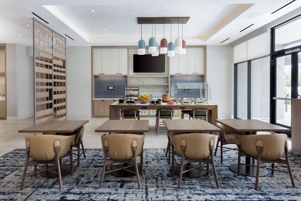 A modern dining area with a central island, multiple tables, and chairs.