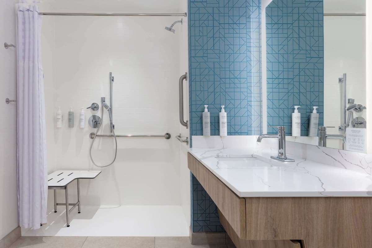 Ein modernes Badezimmer mit Dusche, Waschtisch, Spiegel und Pflegeprodukten.