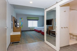 Ein Hotelzimmer mit Bett, Schreibtisch, Stuhl, Fernseher und Kleiderschrank.