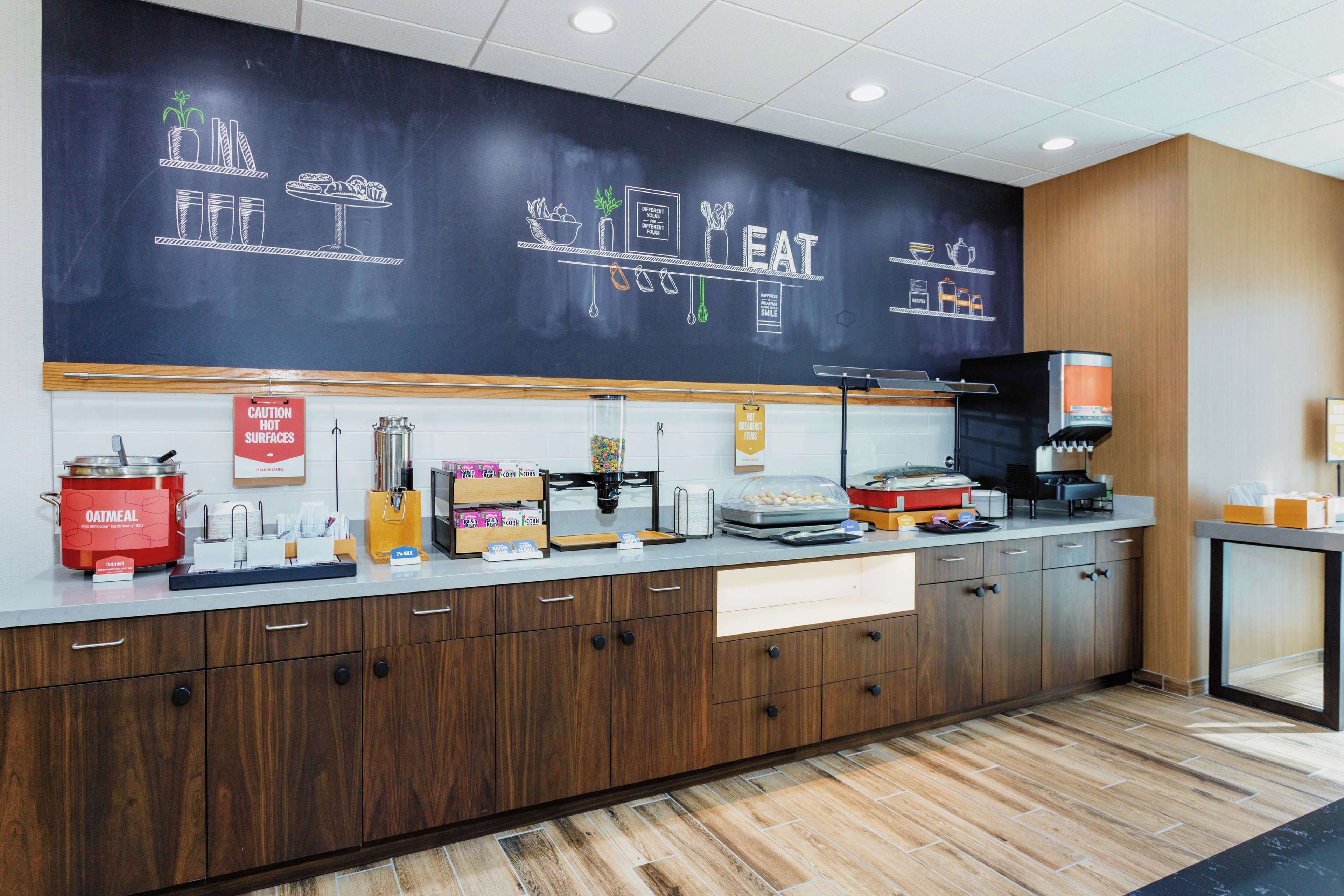 A modern kitchen area with a chalkboard displaying food-related drawings and the word "EAT".