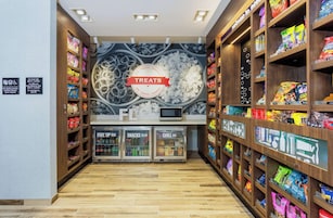Ein Kiosk mit Snacks und Getränken, der eine Auswahl an Speisen und Getränken bietet, darunter eine Abteilung 'Fuel Up' und 'Snacks to Go' sowie ein 'Chill Out'-Kühler.