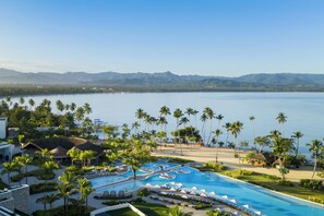 A resort with a large pool, palm trees, and a view of the water. - Zemi Miches Punta Cana Resort, Curio by Hilton (Miches)