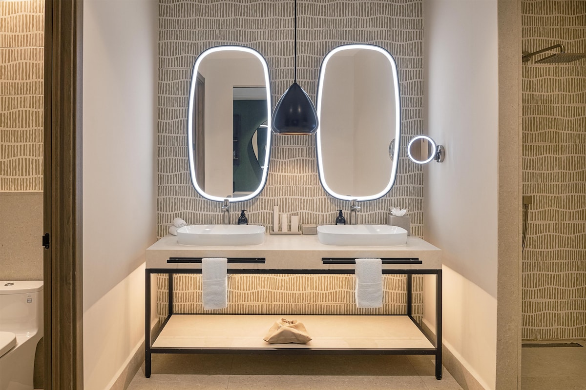 Casa de banho moderna com duas pias, um espelho e um porta-toalhas.