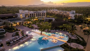 A resort with a large swimming pool, multiple lounge areas, and a view of the surrounding landscape.