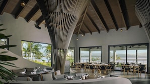 A modern interior with a dining area, large windows, and a view of the outdoors.
