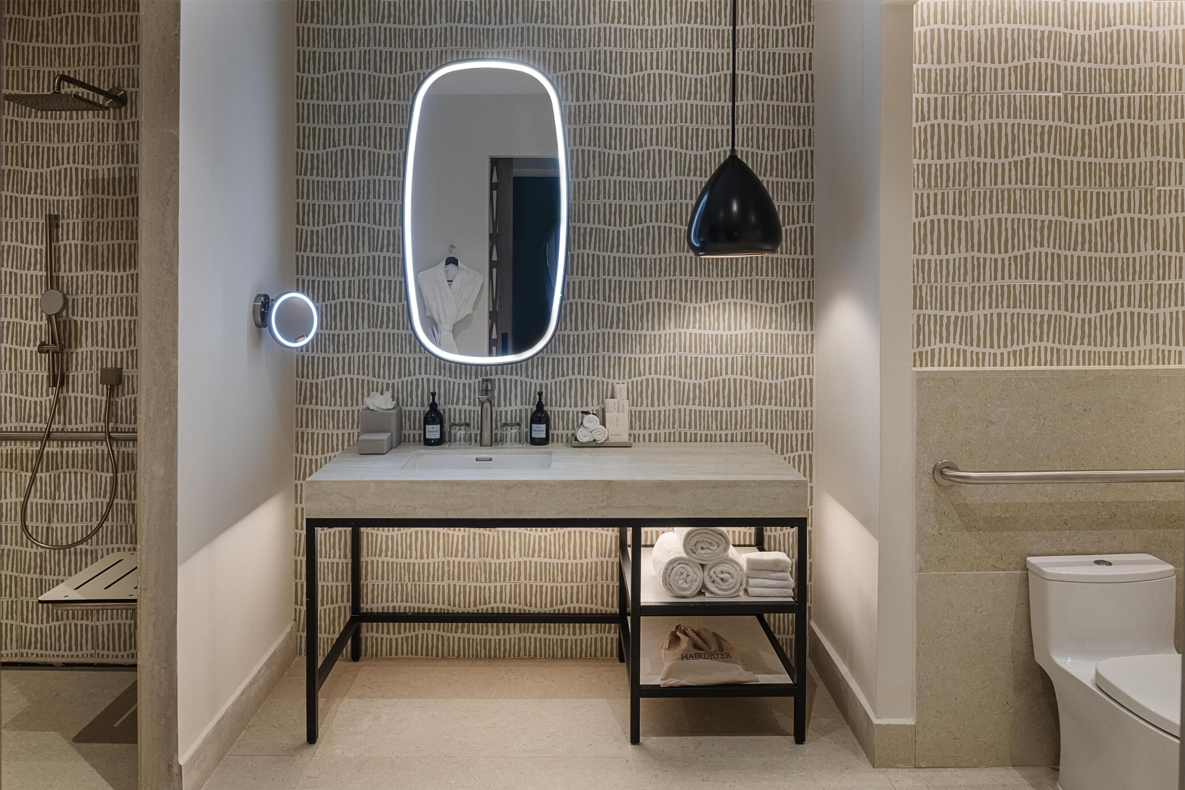 A bathroom with a mirror, sink, towel rack, and shower.