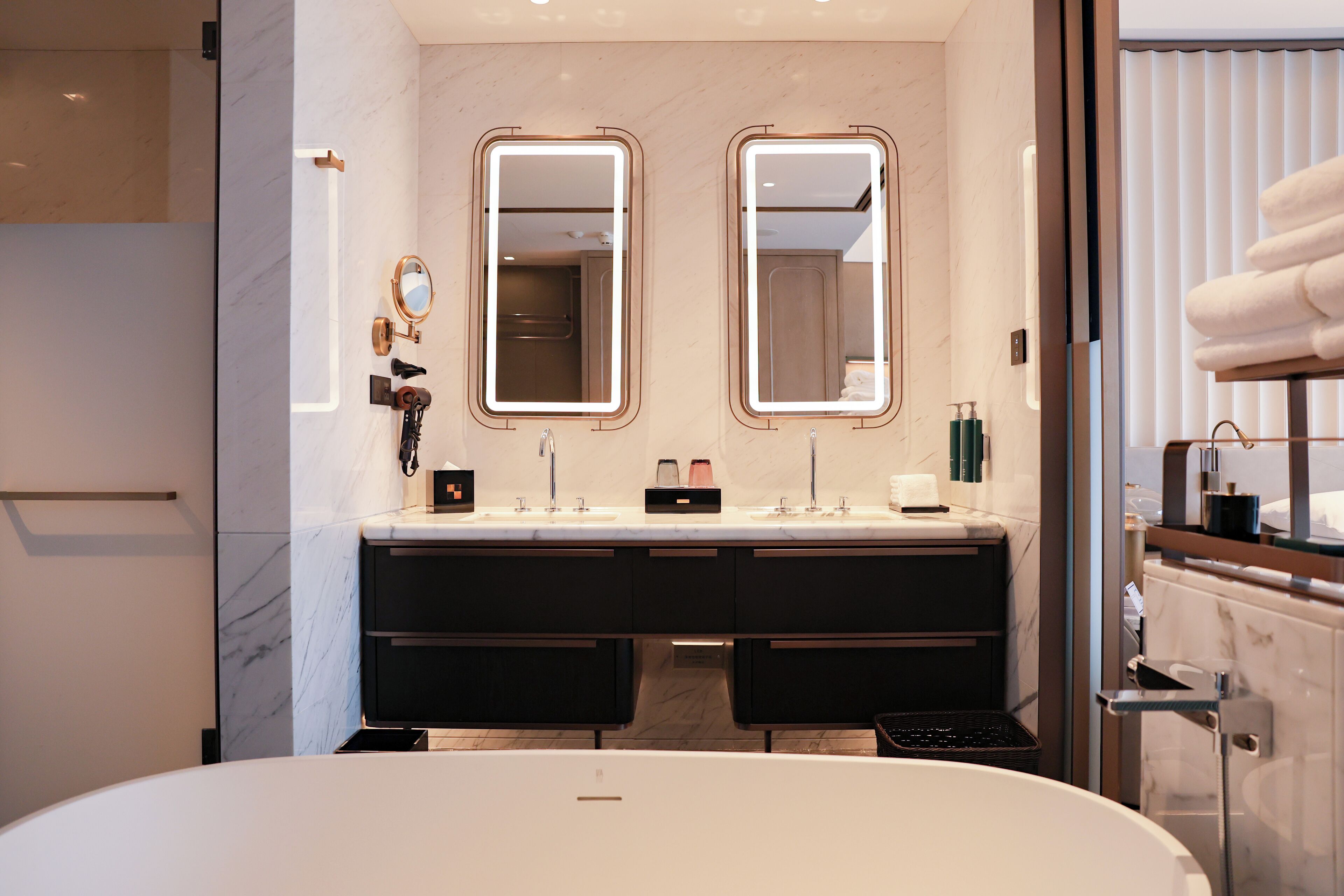 Un baño moderno con una bañera grande, lavamanos dobles y dos espejos fijos en la pared.
