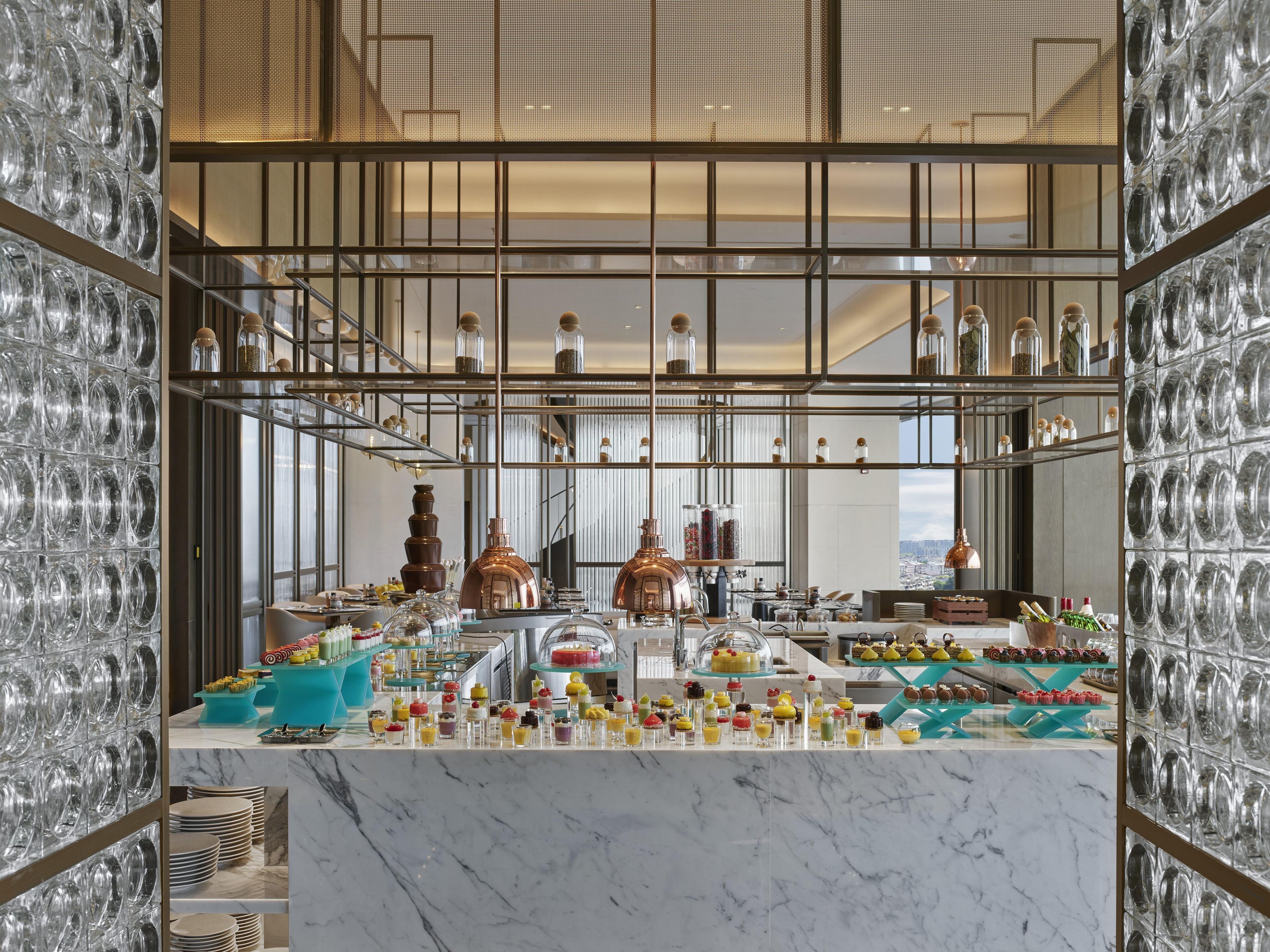 A modern bar area with a marble countertop, glassware, and a variety of food and drink options.