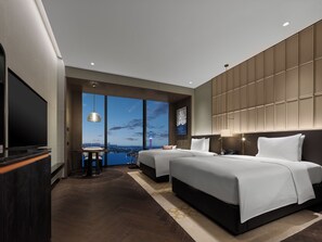 A modern hotel room with a large TV, two beds, a view of the cityscape, and a large window. - Hilton Changshu (Suzhou)