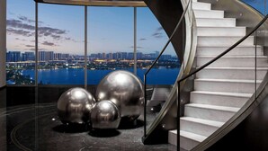 A modern spiral staircase with a city view, surrounded by metallic spheres and a reflective floor. - Hilton Changshu (Suzhou)