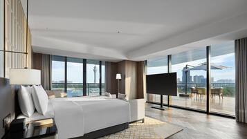 Habitación de hotel moderna con una cama grande, televisión y balcón con vista a la ciudad.