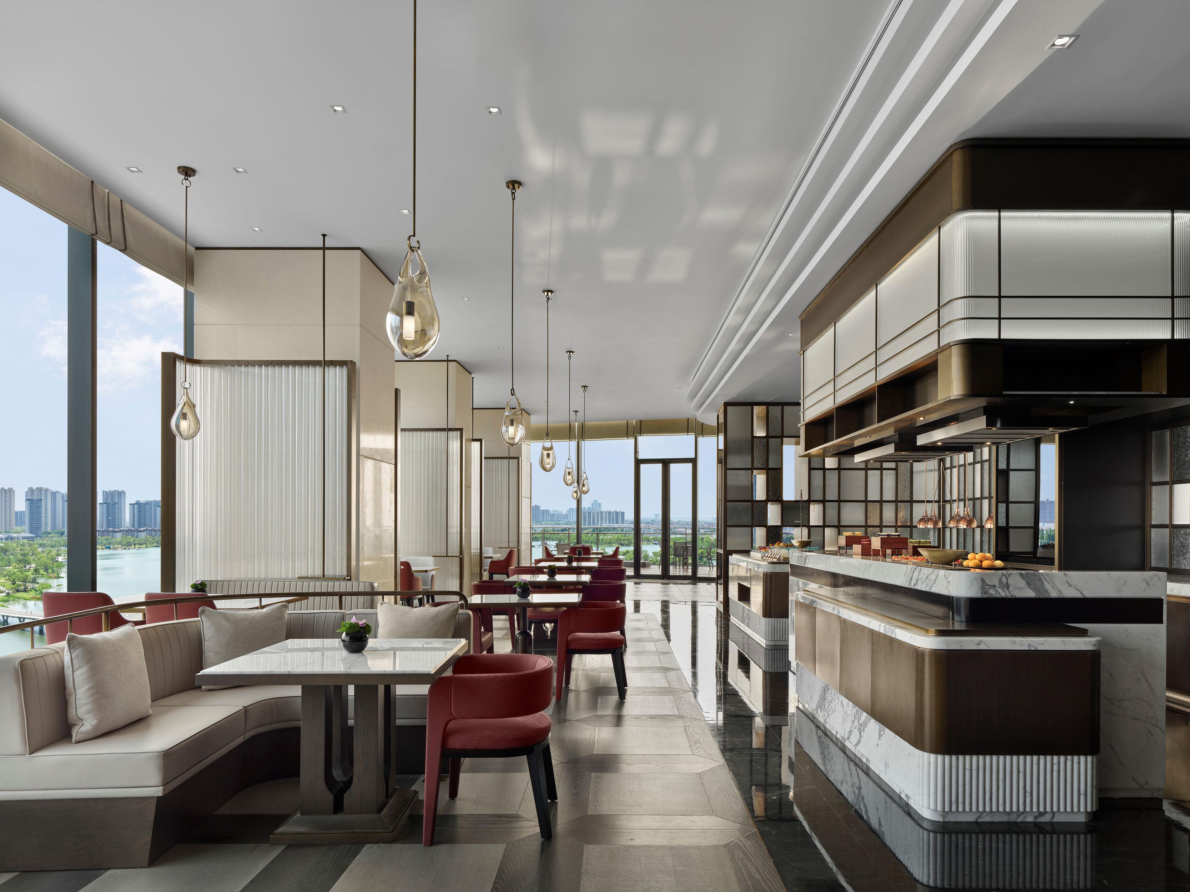Un interior de hotel moderno con comedor, asientos y cocina.