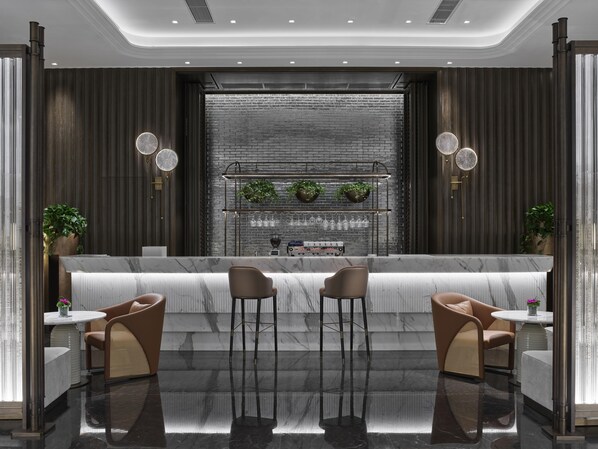 A modern bar area with a marble countertop, two stools, and a brick wall backdrop. - Hilton Changshu (Suzhou)