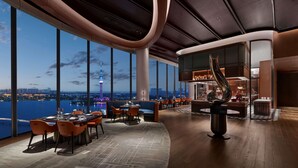 A modern hotel lobby with a panoramic view of a city skyline and a tower. - Hilton Changshu (Suzhou)