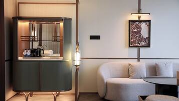 Una habitación de hotel moderna con un armario verde, una mesa redonda, un sofá y una obra de arte enmarcada en la pared.