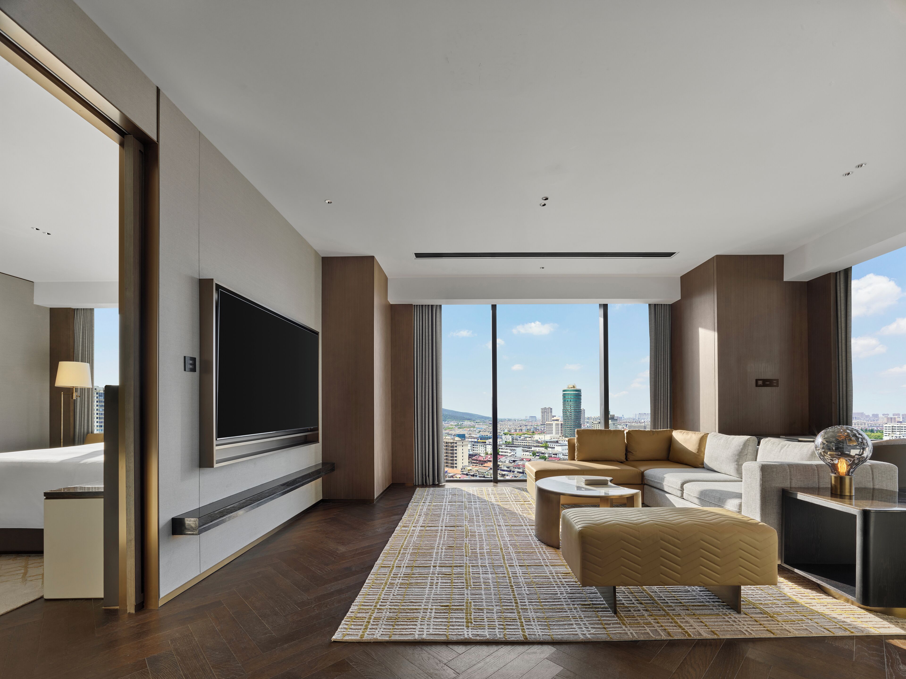 A modern living room with a large TV, comfortable seating, a fireplace, and a city view.
