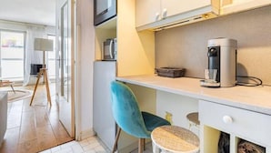 Una cocina compacta con microondas, cafetera y una pequeña mesa.