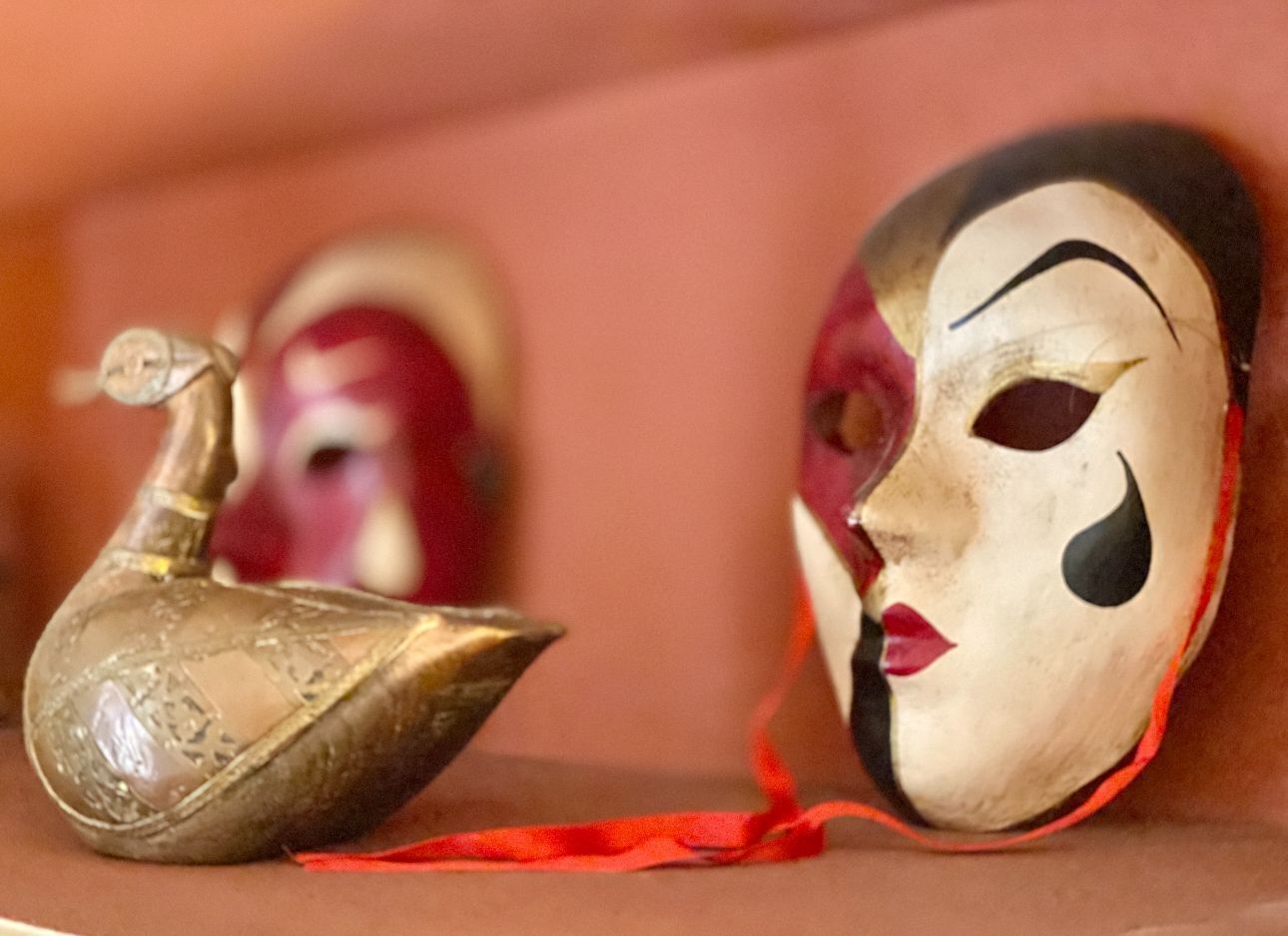 Primer plano de una máscara con un lazo rojo y un pequeño adorno decorativo.