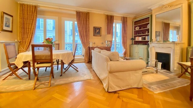A living room with a sofa, a dining table with chairs, a fireplace, and a bookshelf. - Pour un Élégant Séjour aux Invalides - Chevert (Paris)