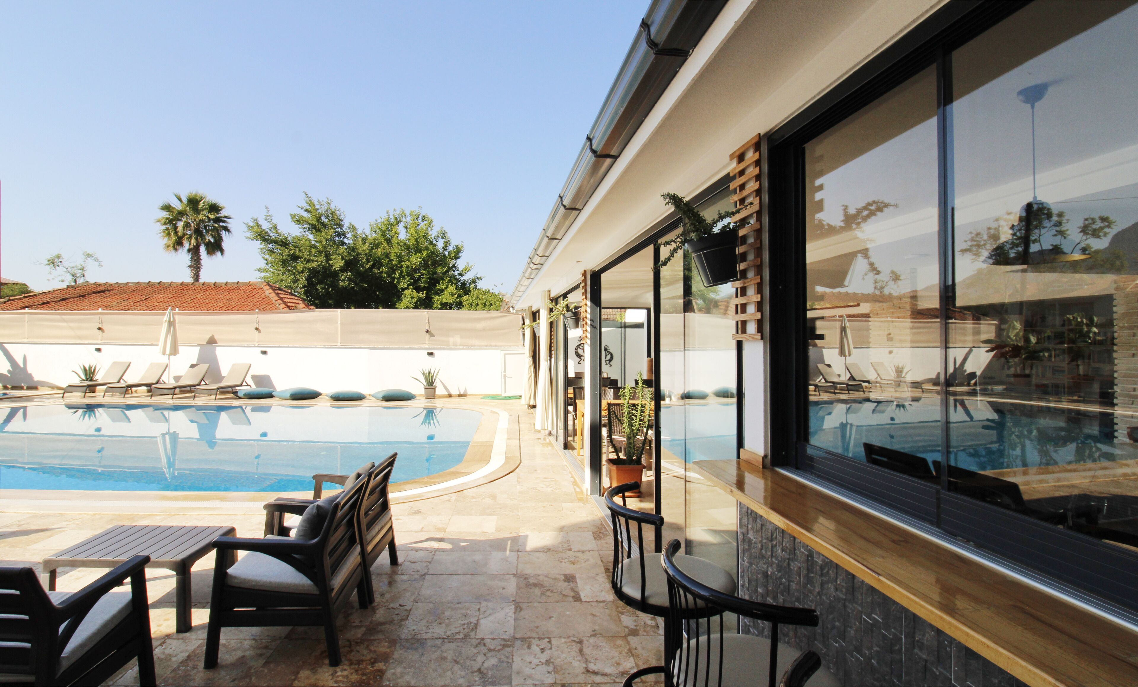 A poolside area with lounge chairs, a table, and a bar area with a view of the pool.
