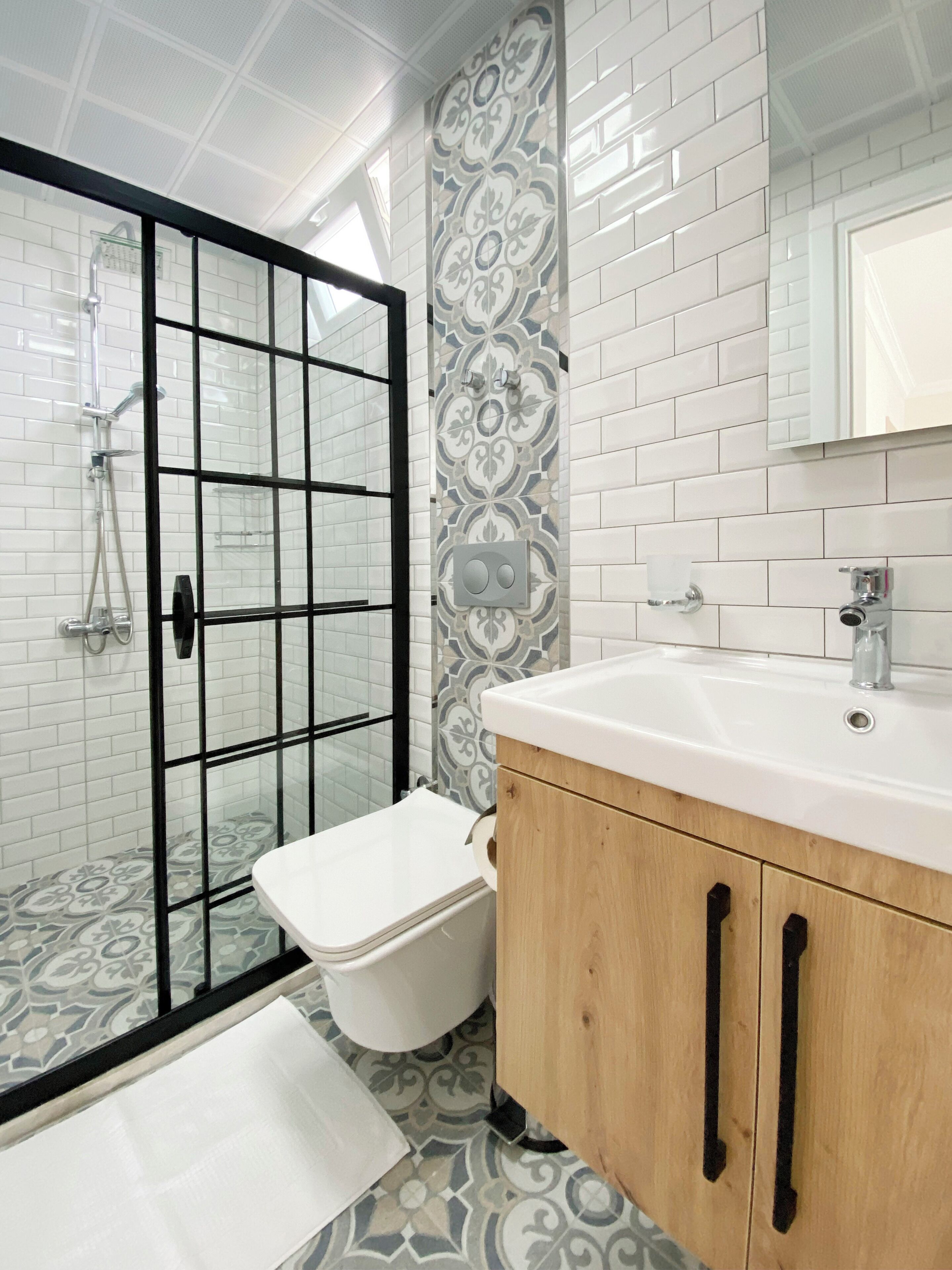 A modern bathroom with a glass shower enclosure, a white toilet, and a wooden vanity with a sink.