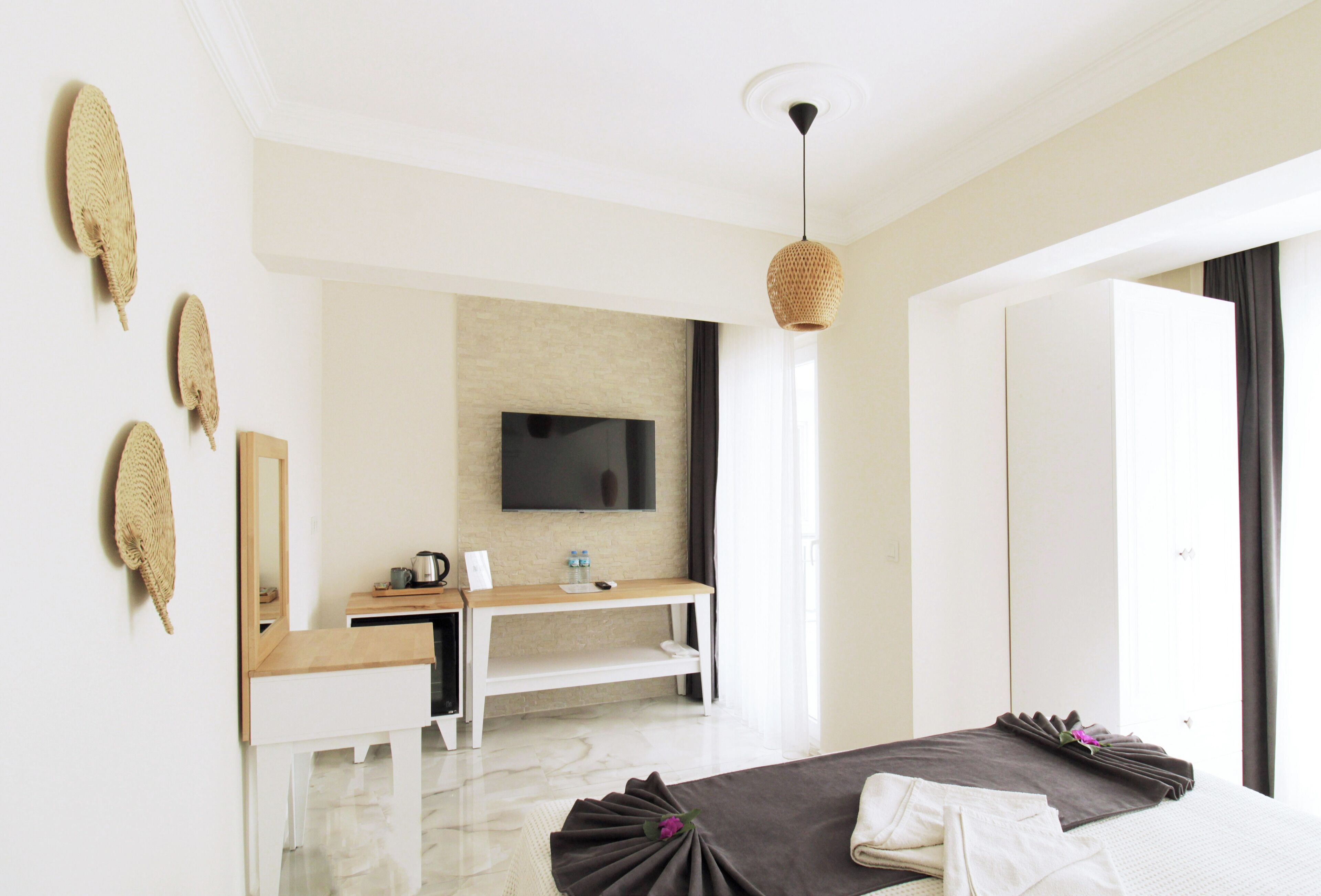 A modern hotel room with a bed, a desk, a flat-screen TV, and a large window.