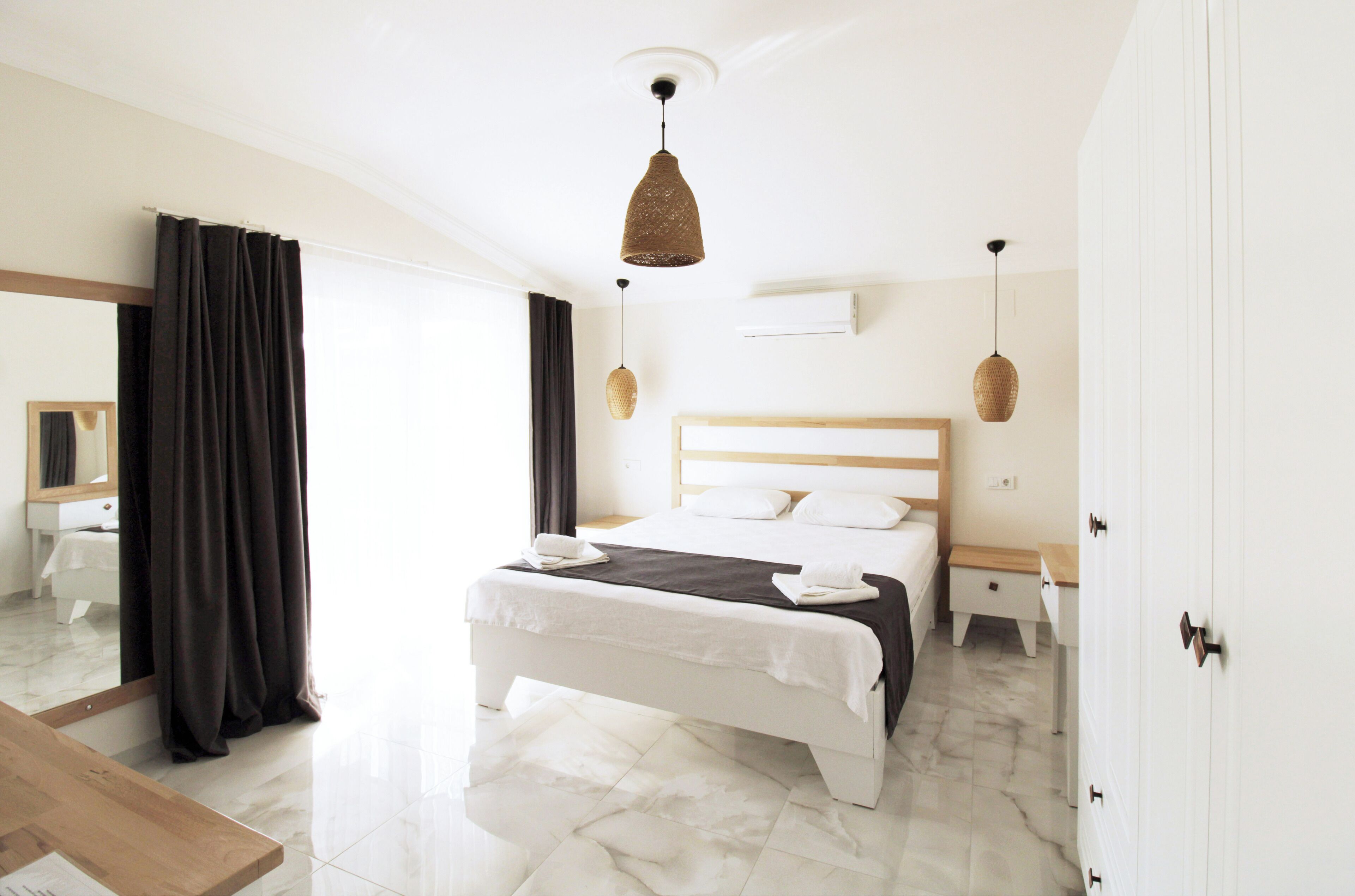 Een moderne hotelkamer met een groot bed, een houten nachtkastje, een bijzettafeltje en een kledingkast.