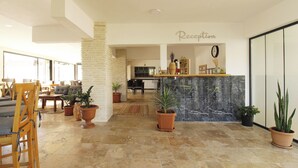 A spacious reception area with a marble counter, potted plants, and a clear view into the dining area. - Tufan Boutique Hotel & Apart (Ortaca)